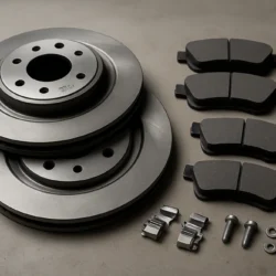 Brake rotors, brake pads, and hardware laid out on a workshop bench, showing components for a Toyota Camry brake kit.